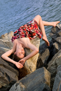 美丽的女孩躺在海上的岩石上