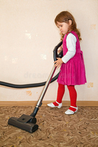小女孩用吸尘器吸地毯