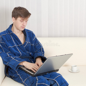 穿着睡衣拿着手提电脑的年轻人