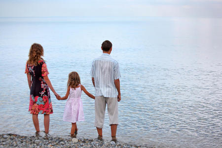 幸福的一家人晚上站在沙滩上
