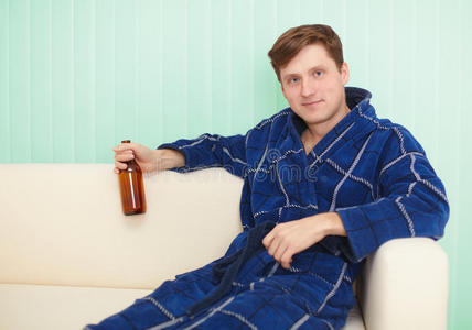 年轻人在沙发上穿着睡衣喝啤酒