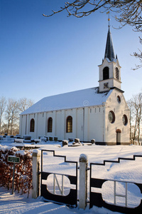 白色冬季景观中的树木和教堂