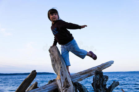 在海滩上的浮木上保持平衡的女孩