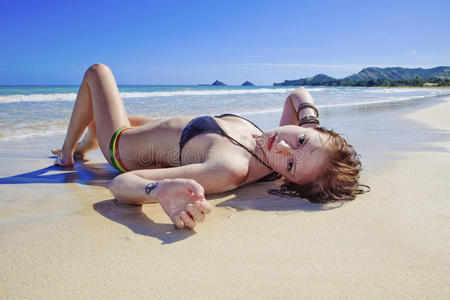 懒洋洋地躺在海滩上的年轻女子图片