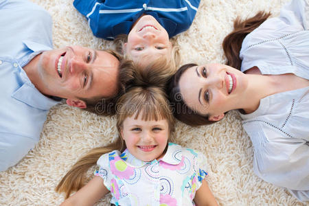 微笑的一家人围成一圈躺在地板上