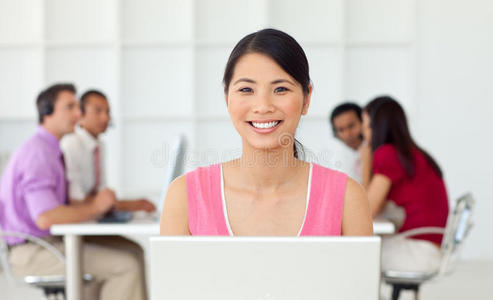 微笑的亚洲女商人对着她的电脑