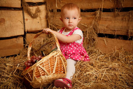 小女孩拿着一篮子水果在稻草上