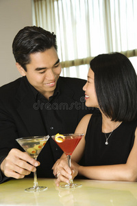 一对迷人的年轻夫妇，喝着鸡尾酒微笑着