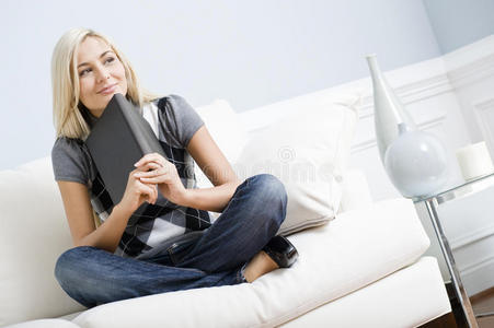 微笑的女人坐在沙发上拿着一本书