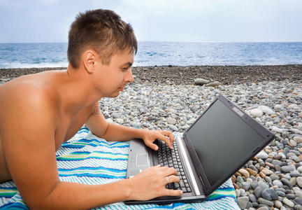 石滩上的男人，看着笔记本电脑屏幕
