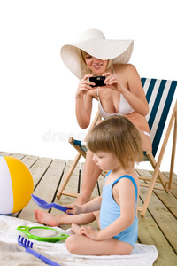 海滩母亲带着孩子用相机拍照图片