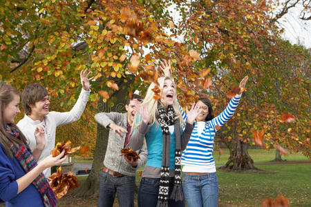 一群年轻的朋友在秋天扔树叶