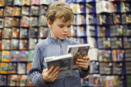 男孩在专卖店挑选两张dvd中的一张