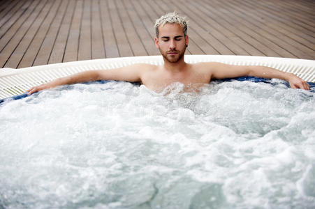 按摩浴缸里的帅哥孩子跳到游泳池,水下景色男人洗脸穿着湿t恤拿着瓶子