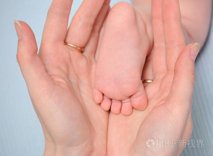 宝贝新生儿的手妈妈的手小心地握住宝宝的脚妈妈手里的小脚丫母亲抱