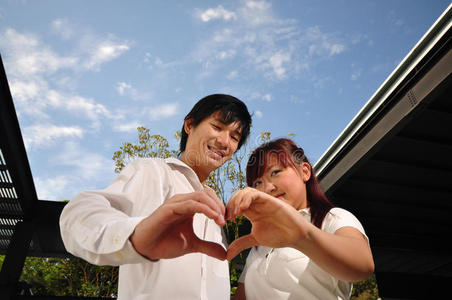 恋爱中的亚洲年轻夫妇形成心形图片