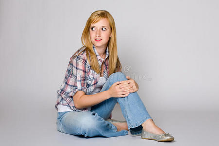 年轻女性坐在地板上，灰色背景