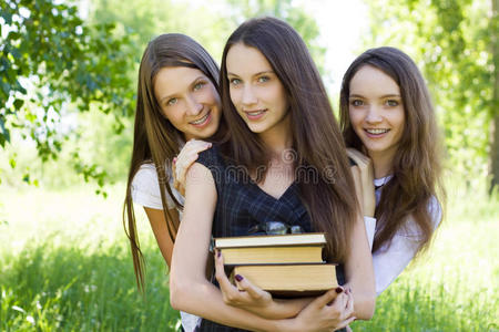 三个快乐的女学生在公园里看书