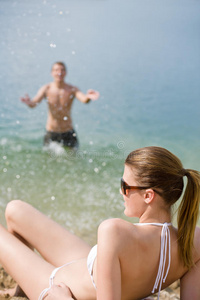海滩上的情侣穿比基尼的女人在海边晒日光浴