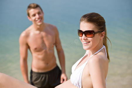 海滩上的情侣穿着泳衣在海边晒日光浴