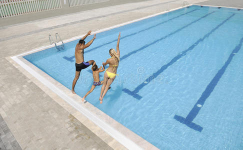 快乐的年轻一家在游泳池玩得开心