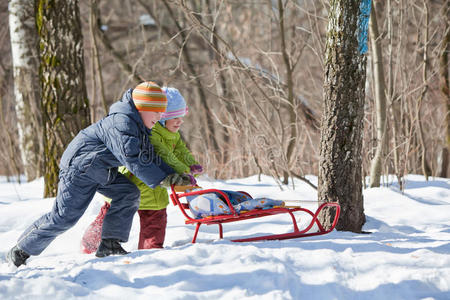 冬天男孩和女孩在树林里推雪橇