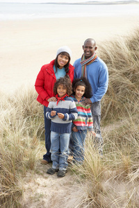 一家人在冬季海滩的沙丘上散步