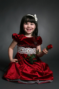 一个小女孩，穿着红色缎子连衣裙和一朵玫瑰