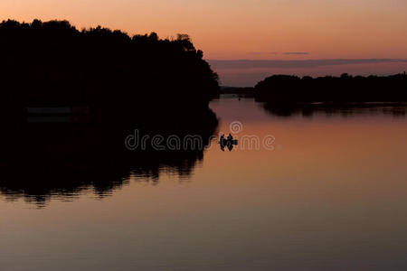 太阳下山后在湖面上漂浮的渔船上的渔民