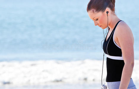 在海滩上听音乐的女运动员