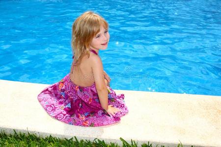 坐在游泳池微笑的金发小女孩