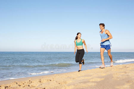 沿着海滩奔跑的年轻夫妇