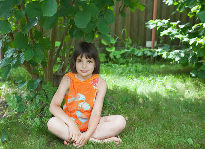 那女孩坐在灌木丛下的草地上