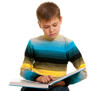 细心瘦小的男孩在读一本厚厚的书