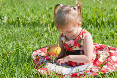 吃苹果在草地上看书的女孩图片