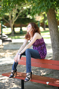 坐在公园长凳上的年轻白人少女