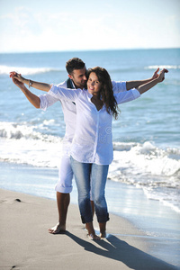 快乐的年轻夫妇在美丽的海滩上玩得开心