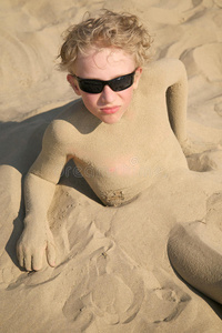 戴着太阳镜在沙滩上放松的男孩