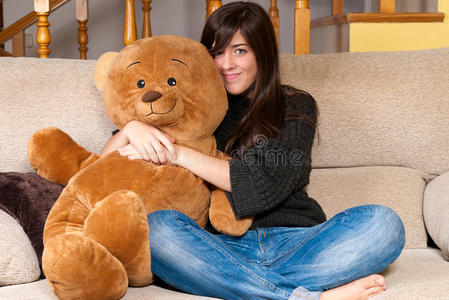 坐在沙发上抱着泰迪熊的年轻女子
