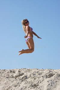 穿游泳衣的女人跳在沙滩上图片