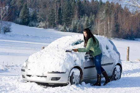 冬季汽车女人清除挡风玻璃上的雪