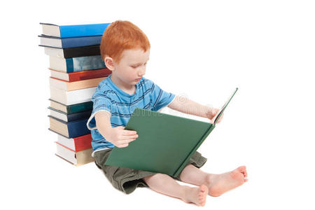 男孩阅读儿童读物，倚靠叠叠的书