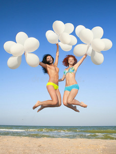 两个快乐的女孩拿着白色气球跳