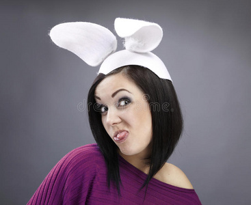 一个滑稽的黑发女郎，穿着一件亮毛衣，有一只兔耳朵