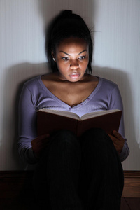 读恐怖惊悚小说的年轻黑人妇女图片