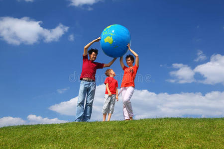 一家人在草地上举起一个充气的地球仪