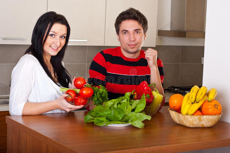 欢快的年轻夫妇在厨房里吃蔬菜图片