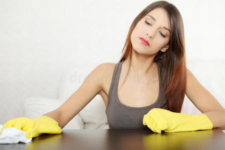 疲惫不堪的年轻妇女在打扫家具桌