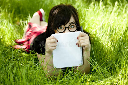绿草地上拿着笔记本的年轻女孩