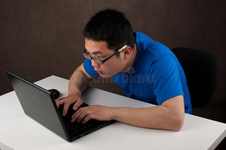 一个年轻的亚洲人在他的笔记本电脑上工作